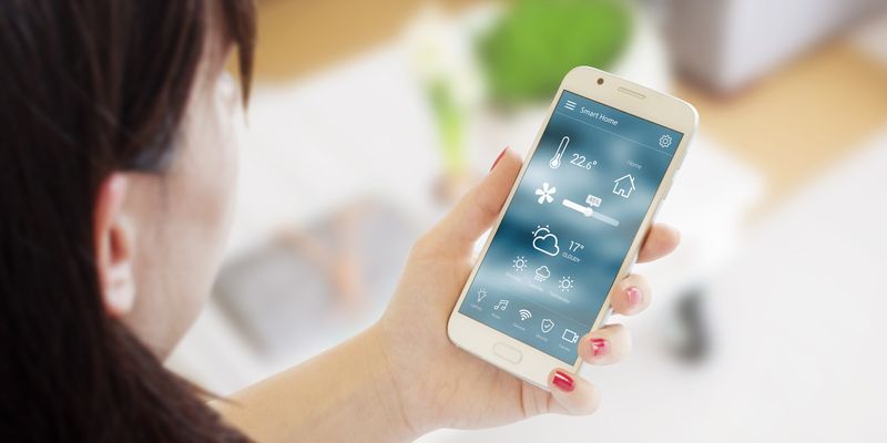 Kvinne ser på en smarthjemapp på mobilen