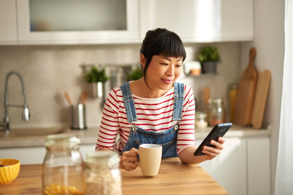Femme qui regarde son smartphone pour contrôler sa borne de recharge