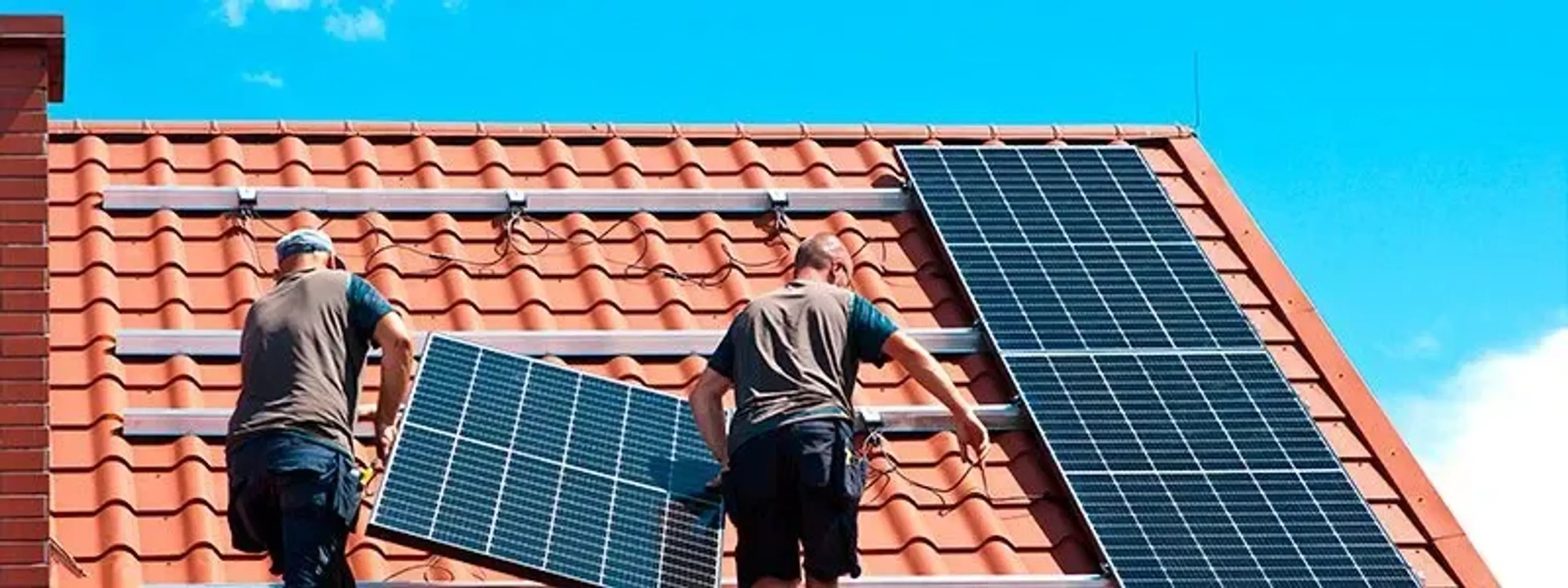 To solcellemontører i gang med at installere solceller på et tag.