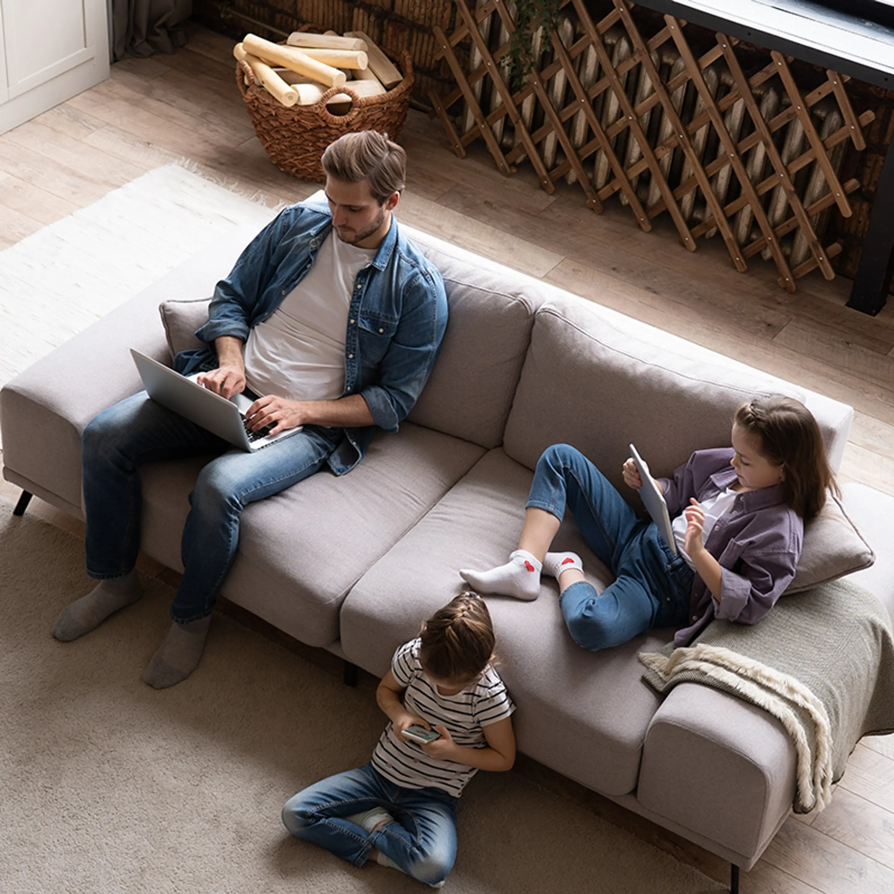 Bilde av en far og to barn som sitter ved en sofa på hver sin skjerm.