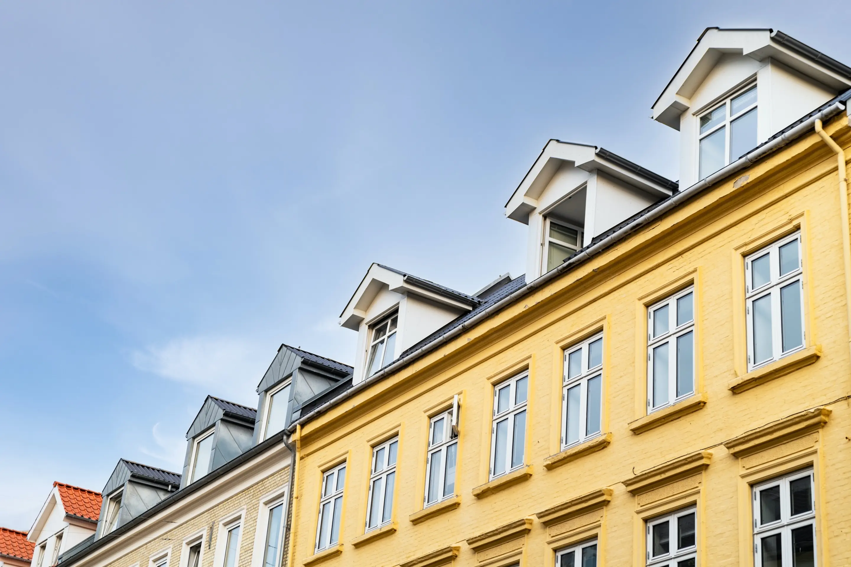 Bilde av en gulmalt bygning med en blå himmel over.