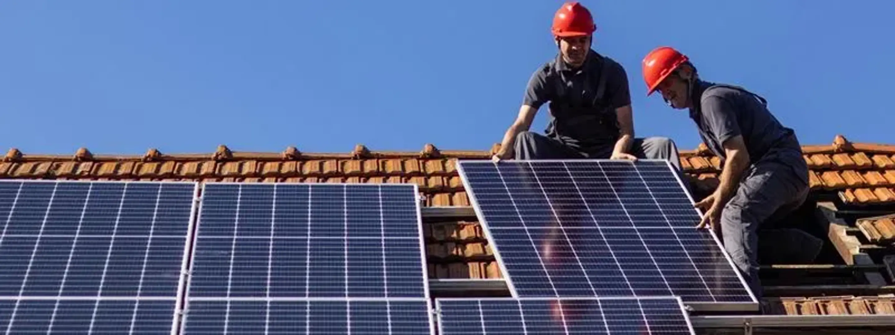 To solcellemontører i arbejde på et tag.