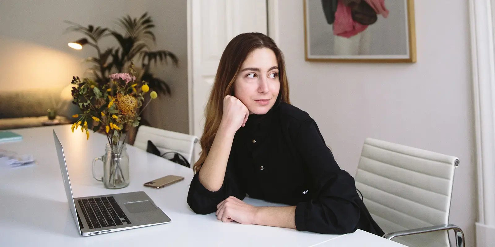 Bilde av en kvinne som ser til høyre mens hun sitter ved en pult med en laptop på.