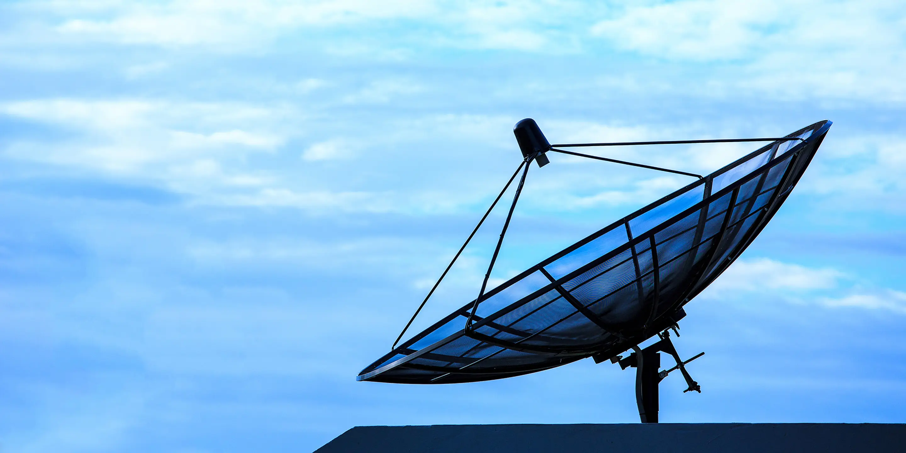 Bilde av en satellittantenne med blå himmel i bakgrunnen.