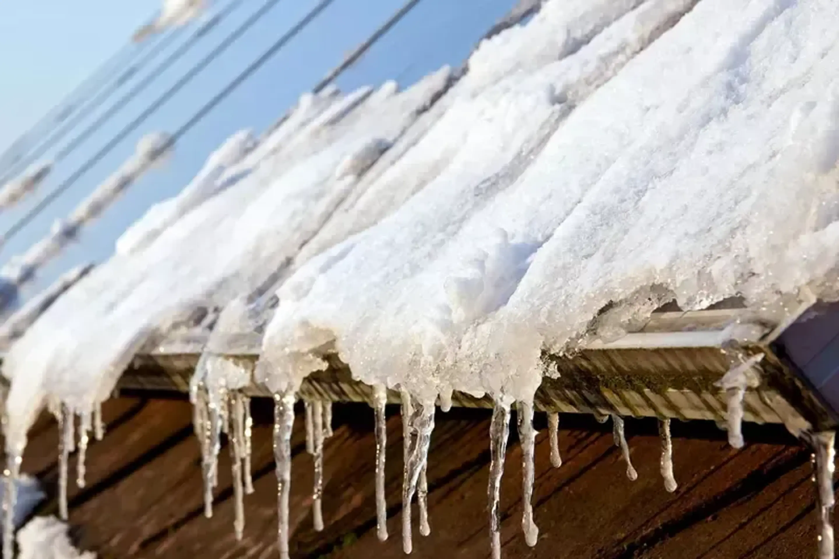 Istappar hänger ner från ett tak med solpaneler.