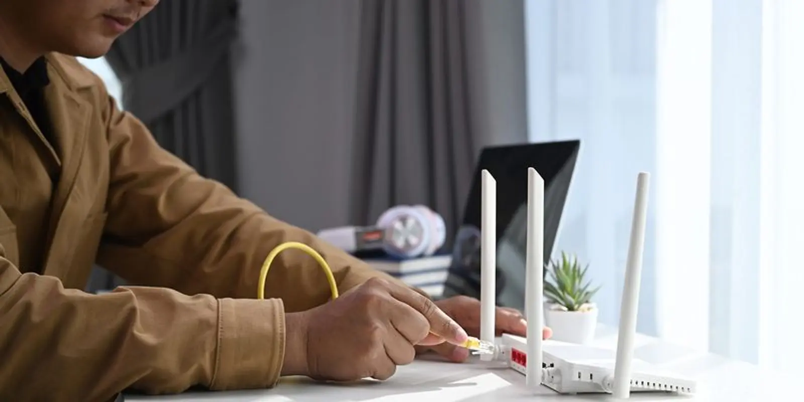 Person som kobler til en ethernet kabel inni en ruter