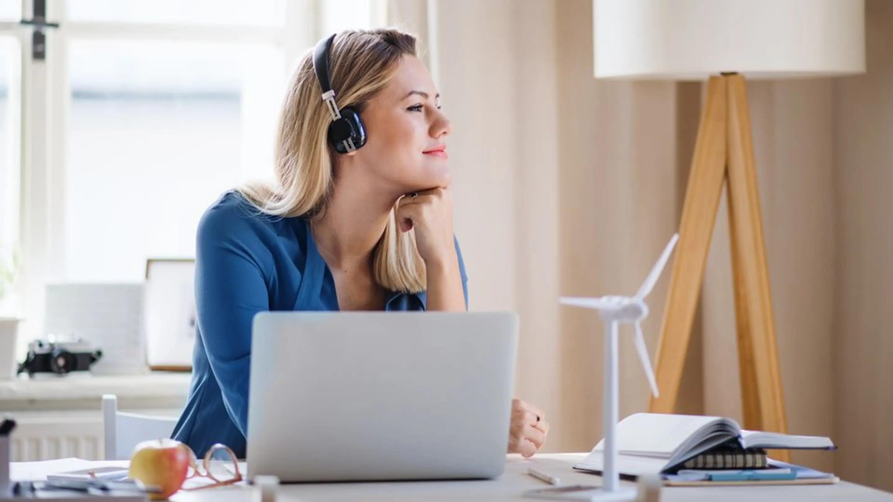 Bilde av en kvinne som sitter på en pult foran en laptop og ser til høyre.