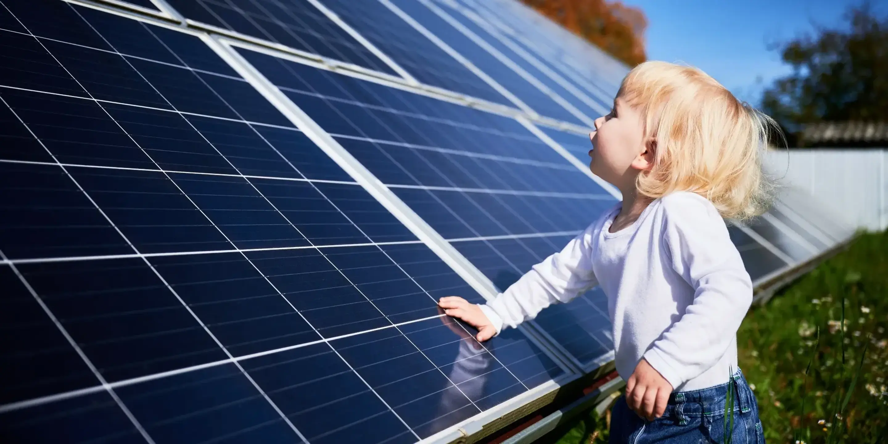 Ett litet barn som står bredvid stora solpaneler.