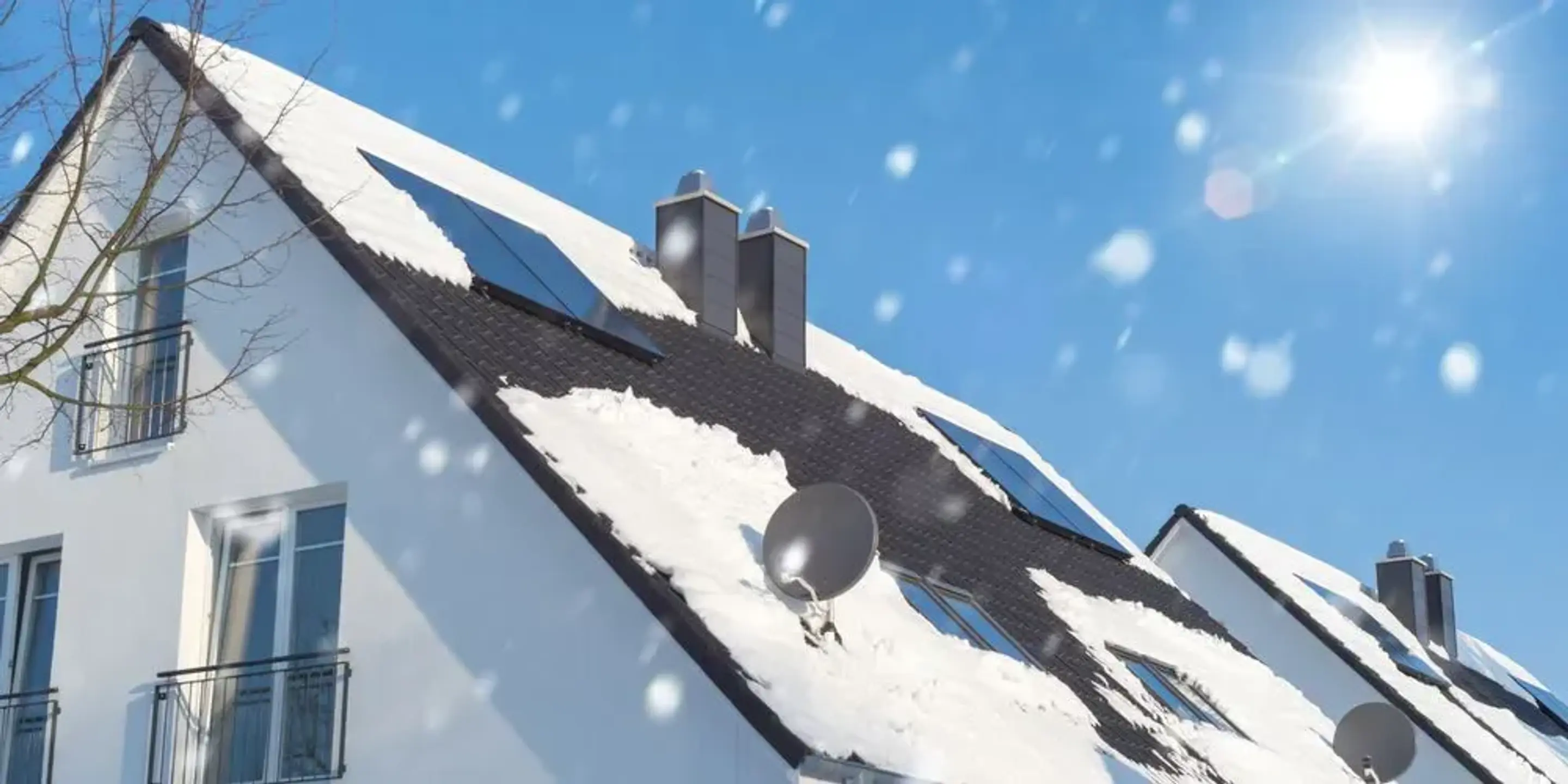 Solceller på ett snöigt tak med blå himmel i bakgrunden.