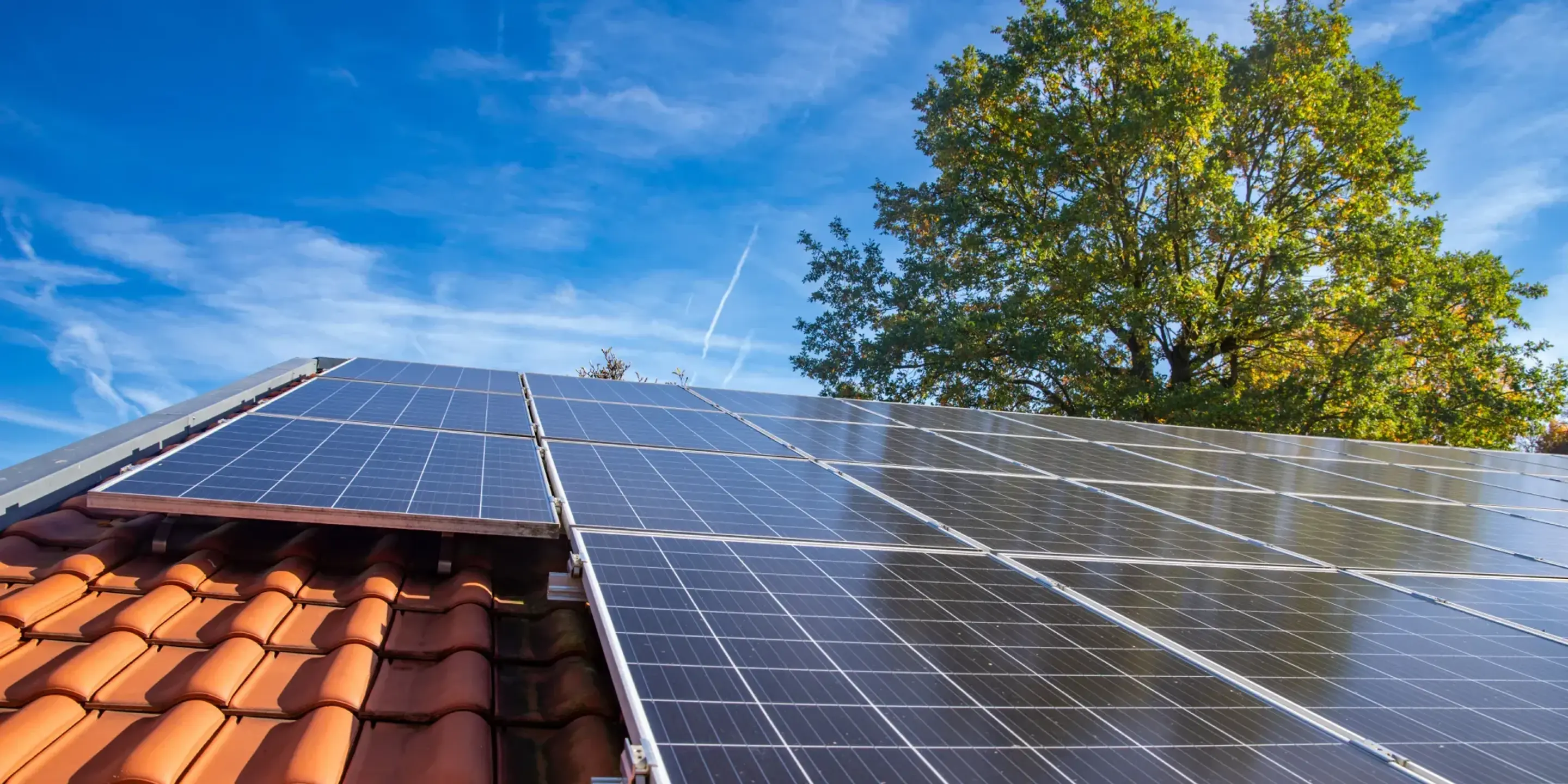 Solcelleanlæg monteret på et hus med rødt tag