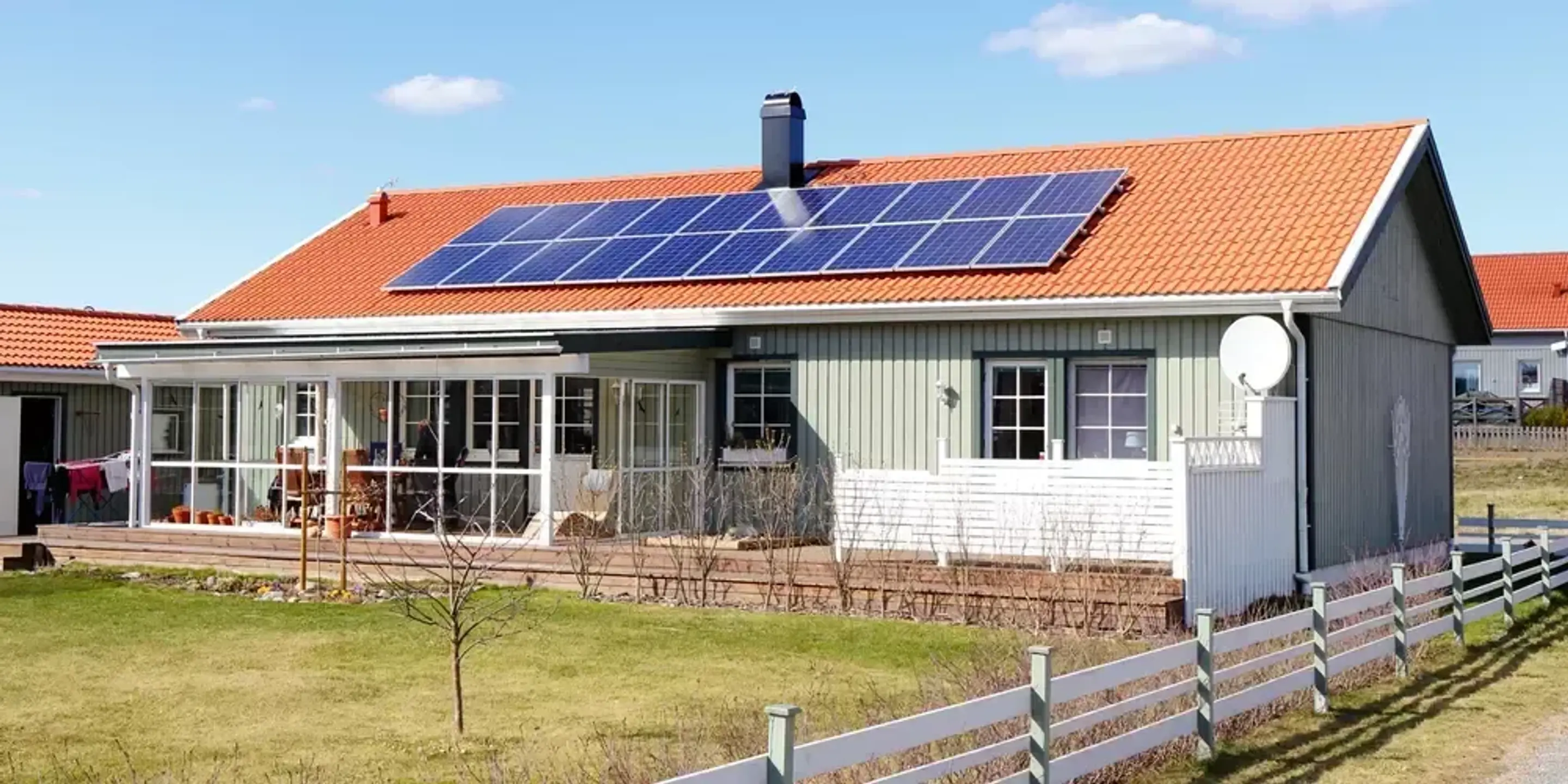 Solcellspaneler installerade på en ljusgrön villa i solsken.