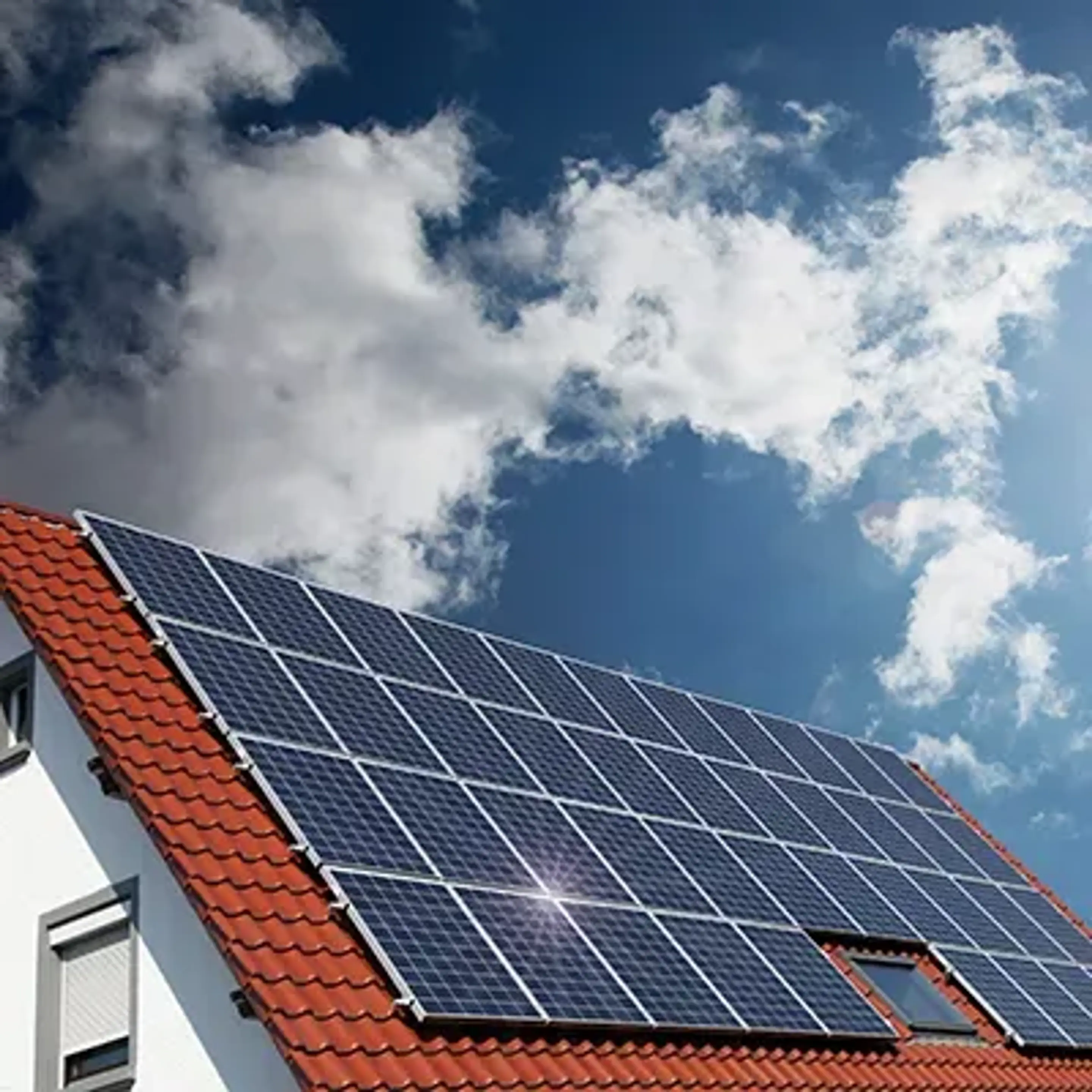 Solen skiner på solceller på ett villatak.