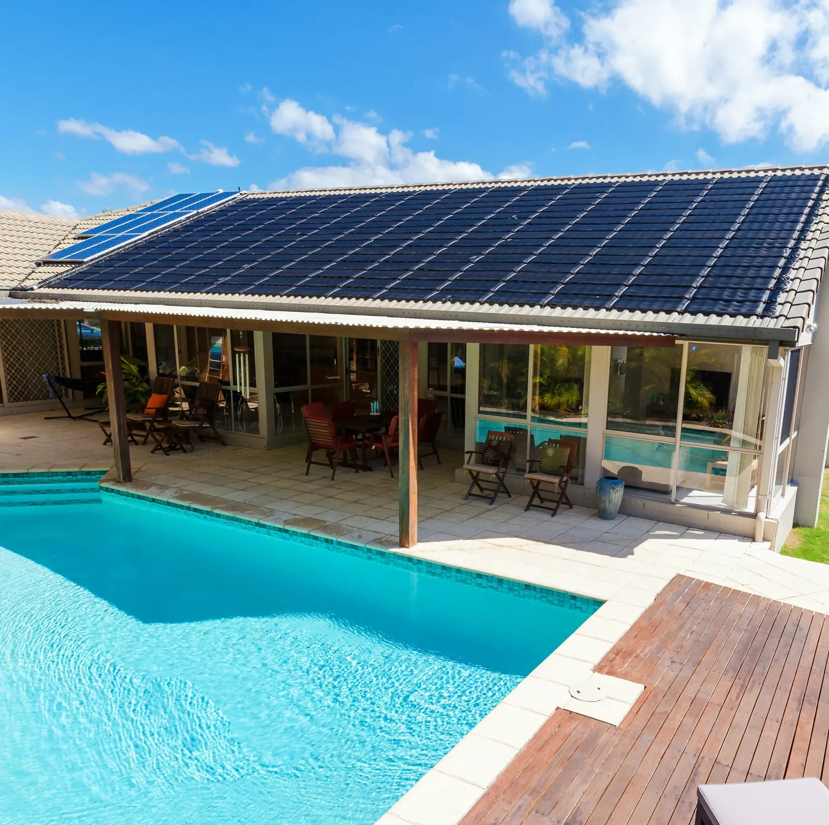 Villa med solfångare på taket och en pool på tomten.