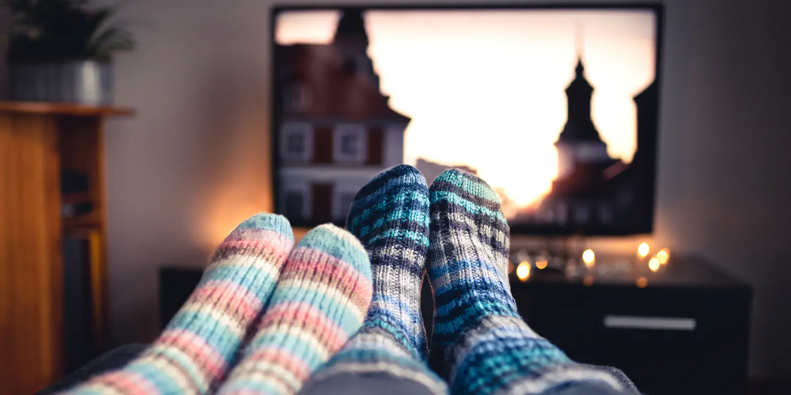 Bilde av to par føtter med ullsokker foran en TV