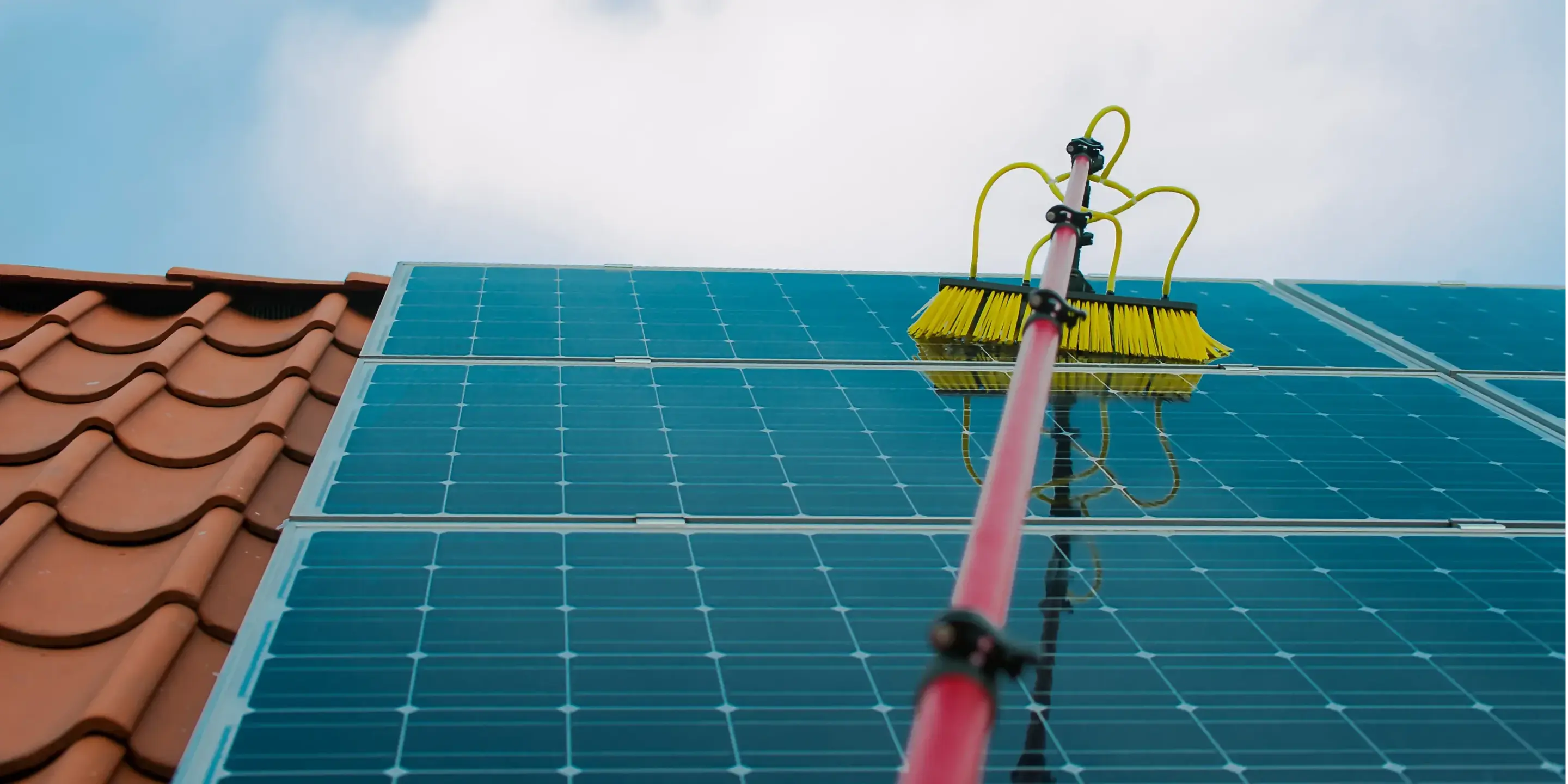 Renöring av solceller på tak med borste.