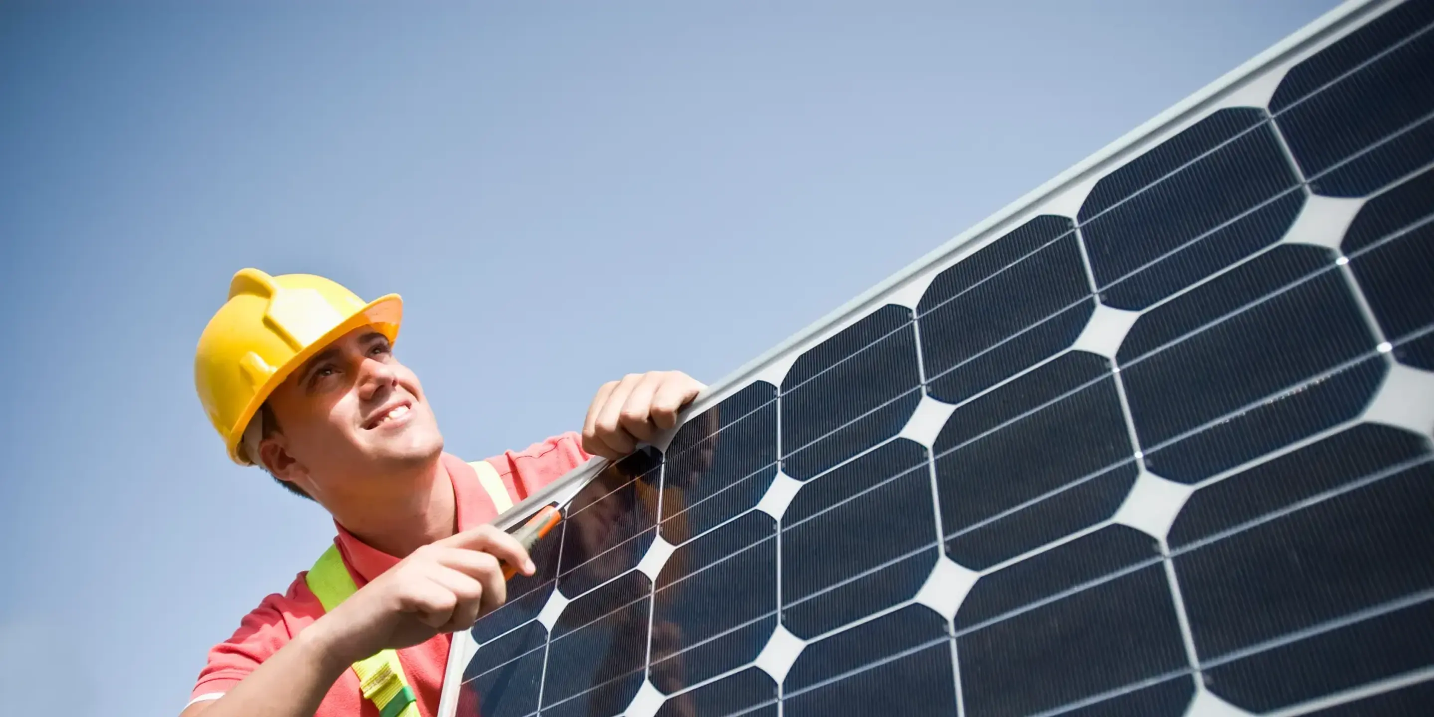 En solcellsinstallatör monterar solceller och kollar åt höger.