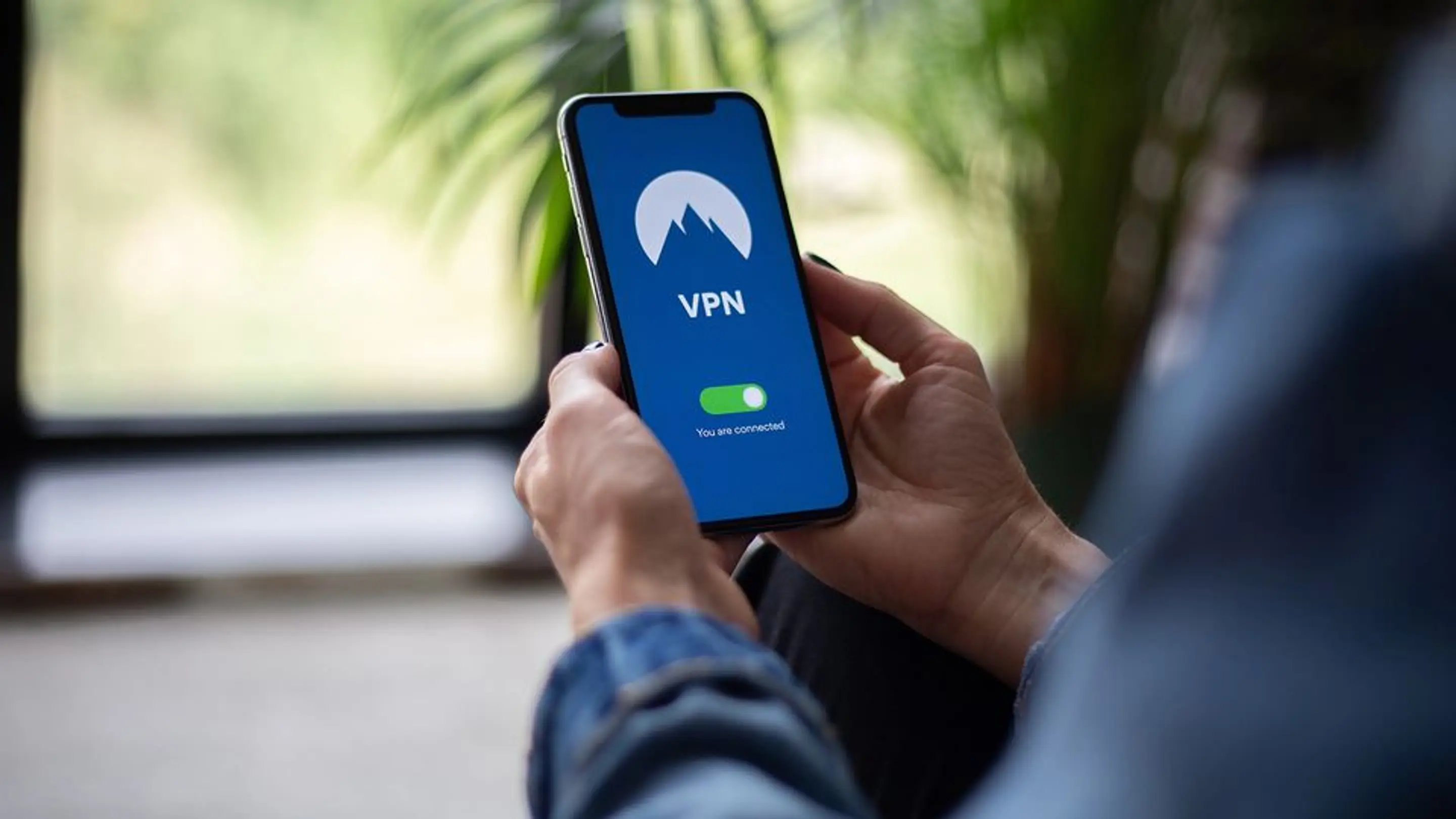 Bilde av en person som holder en mobil i hånda hvor VPN er skrudd på.