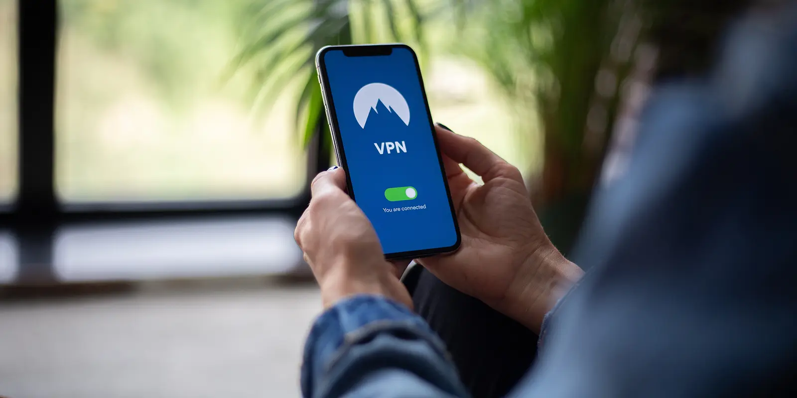 Bilde av en person som holder en mobil i hånda hvor VPN er skrudd på.