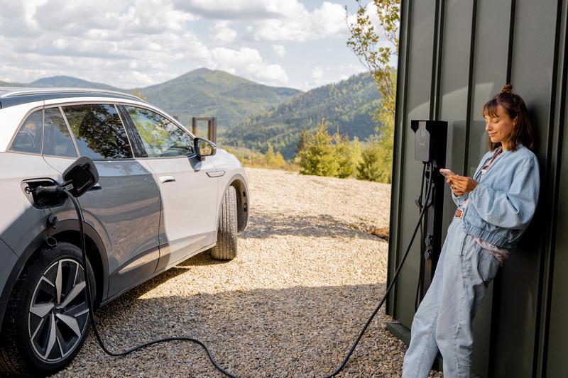Bilde av dame som lader elbil hjemme med veggmontert ladeboks.