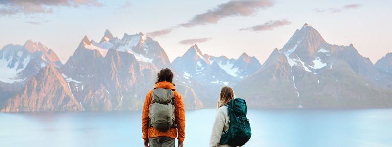 Bilde av to turgåere i et landskap med fjell