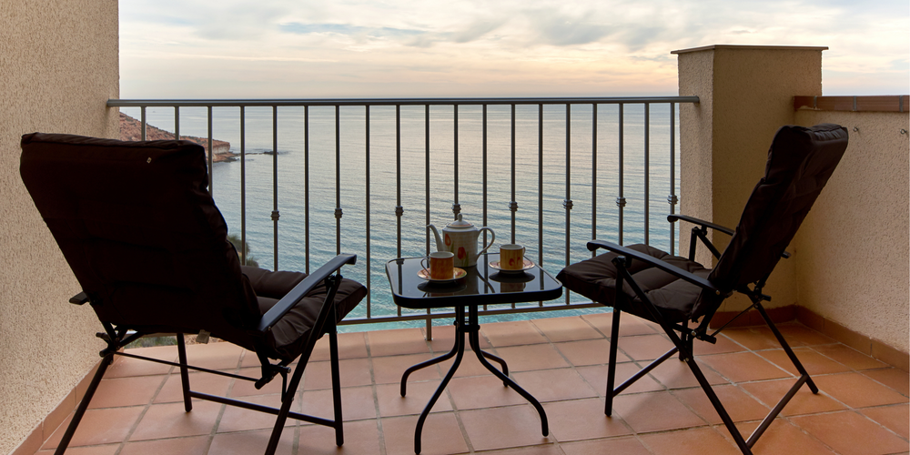 Morgonkaffet och kvällskoppen här? En flytt till Spanien ger förhöjd livskvalitet. Balkong med två stolar och kaffe med utsikt över Medelhavet.