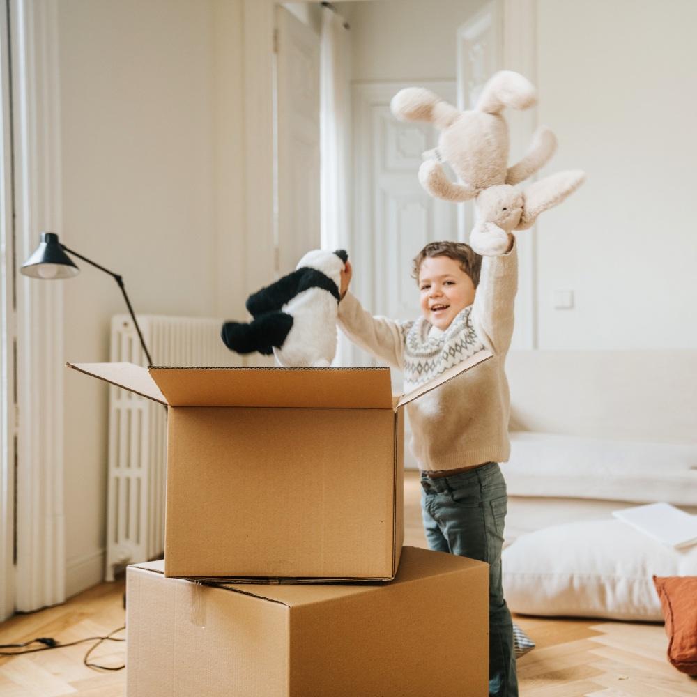 En 5-årig pojke packar upp sina gosedjur ur en flyttkartong.