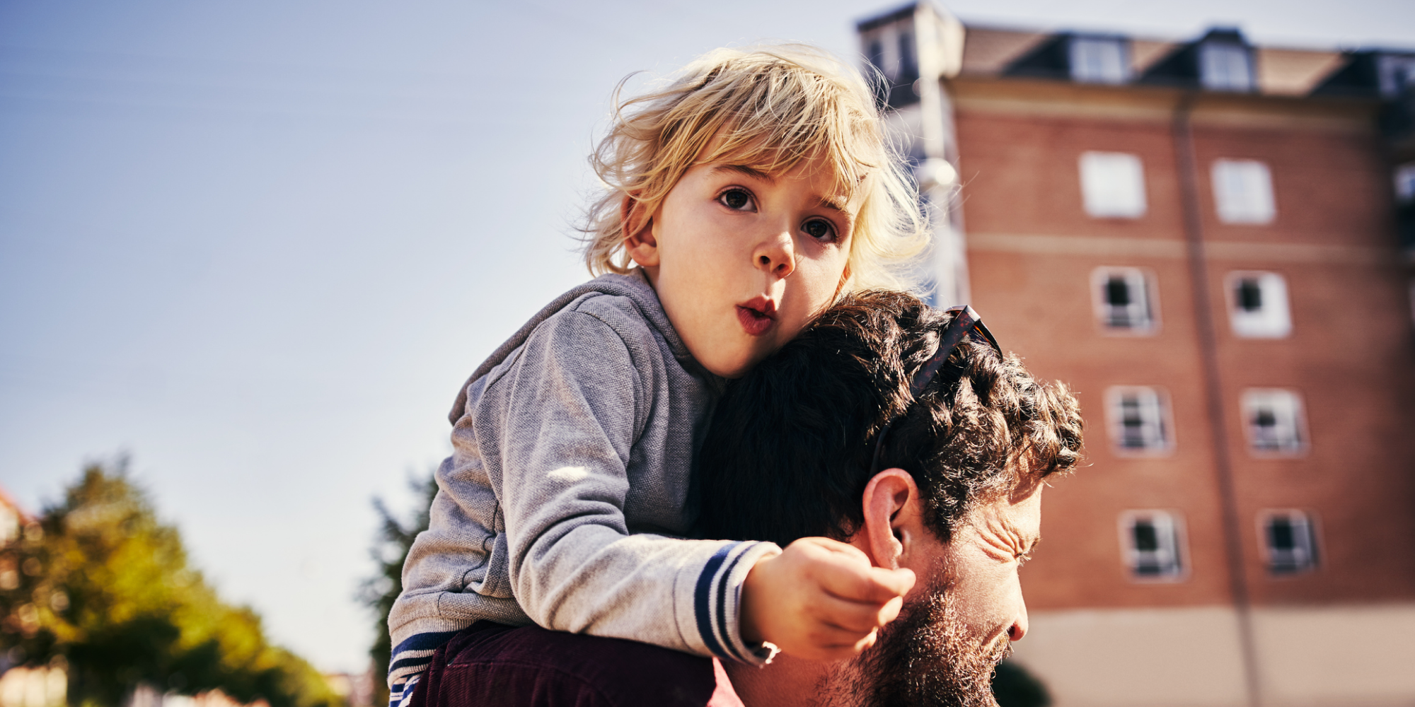 Barn som sitter på sin förälders axlar i stadsmiljö.