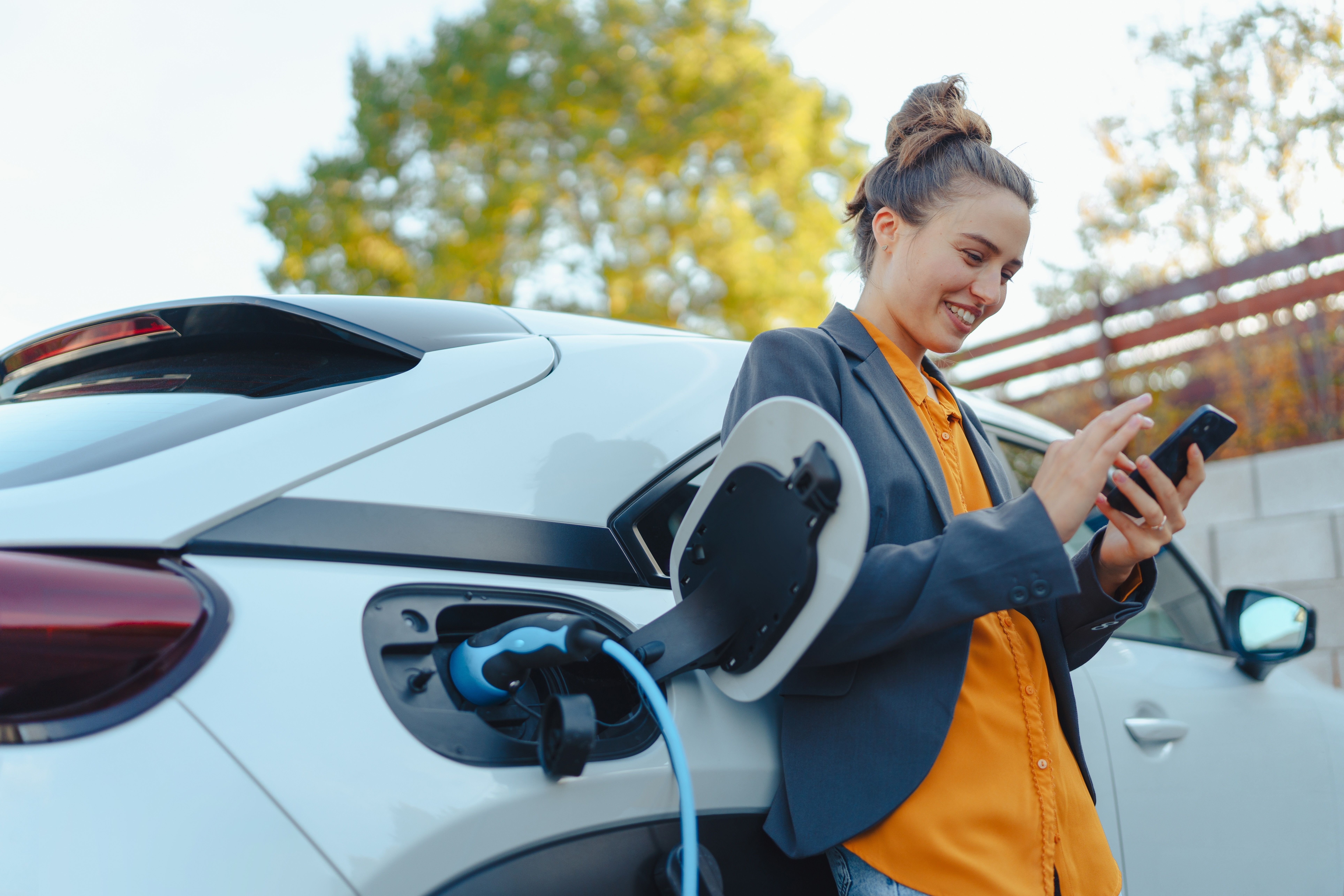 A person looking at their phone while their EV charges