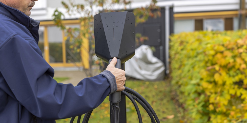 En man använder sin egen laddstolpe.