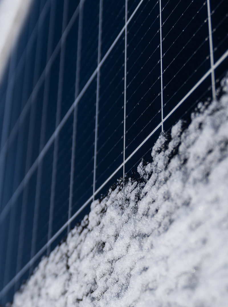 Närbild på solpanel delvis täckt av snö.