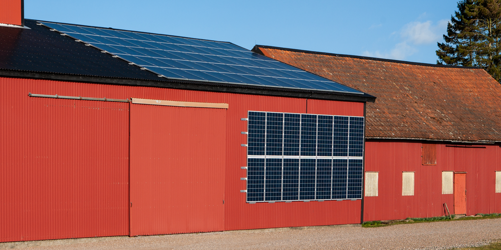 Med solceller på både vägg och tak kan du maximera produktionen av egen el. Röd ekonomibyggnad med solceller på tak och vägg.