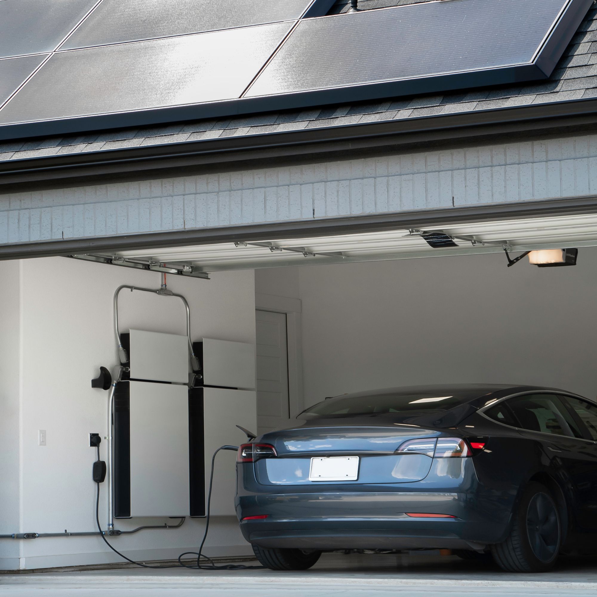 En elbild laddas i ett garage med installerade solceller och solcellsbatterier.