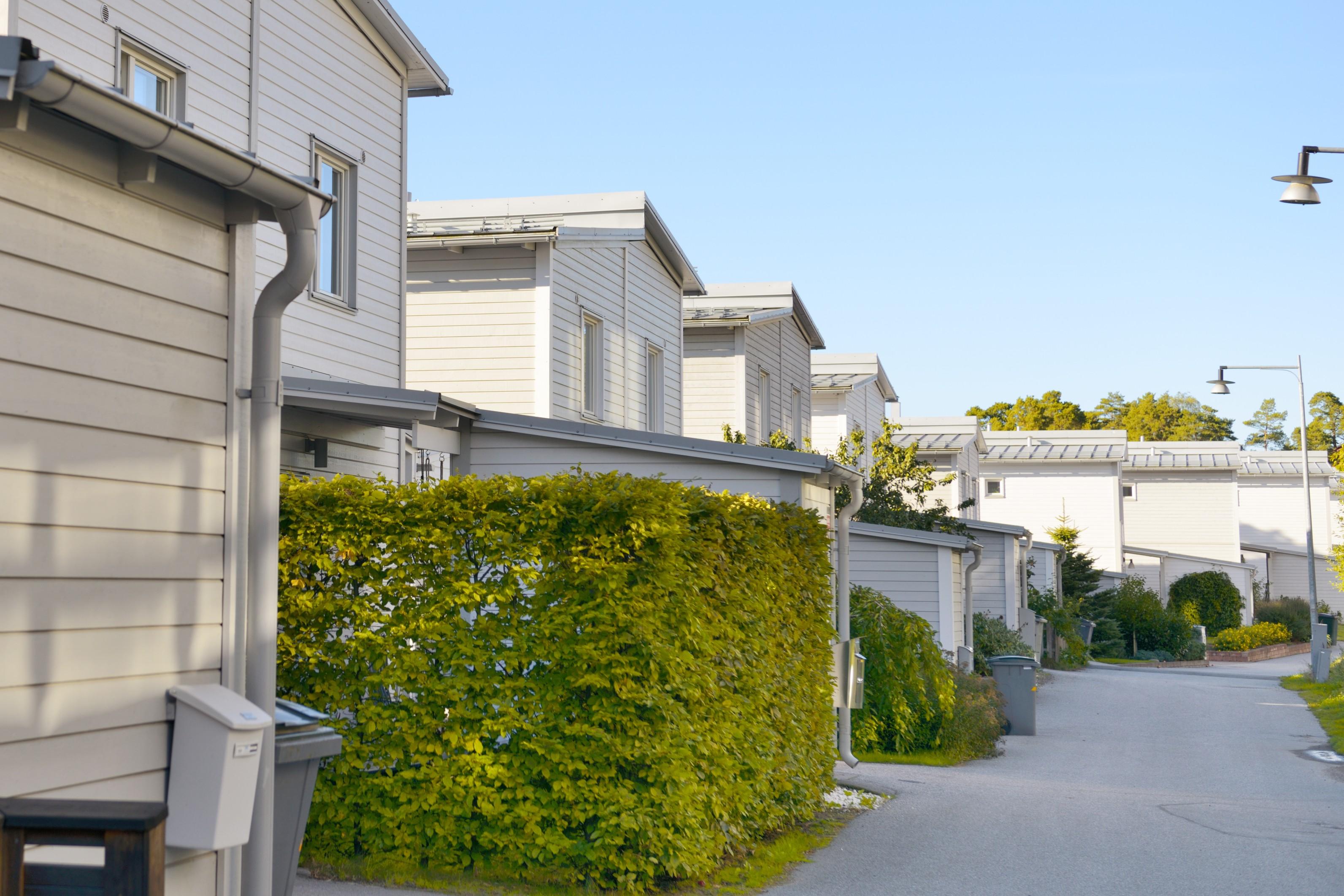 Gråa kedjehus i en typisk svensk bostadsmiljö.