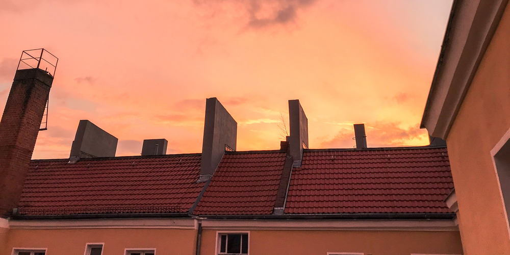 Rosa solnedgång över hustak.