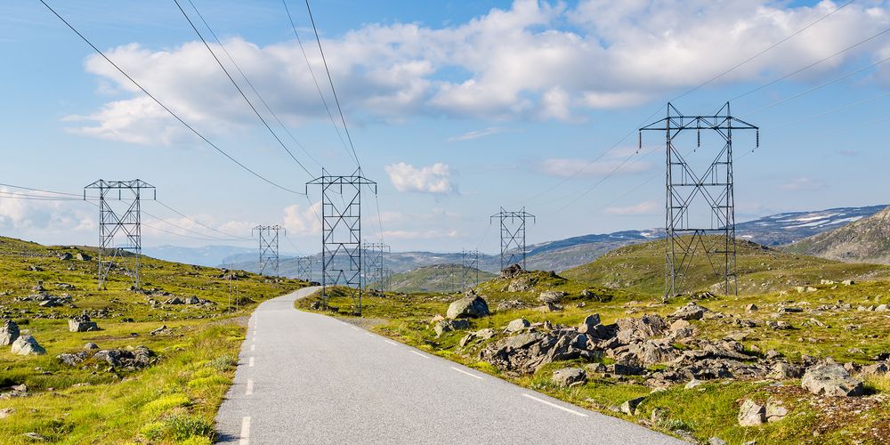 Bilde av en norsk landevei med store strømmaster på begge sider.