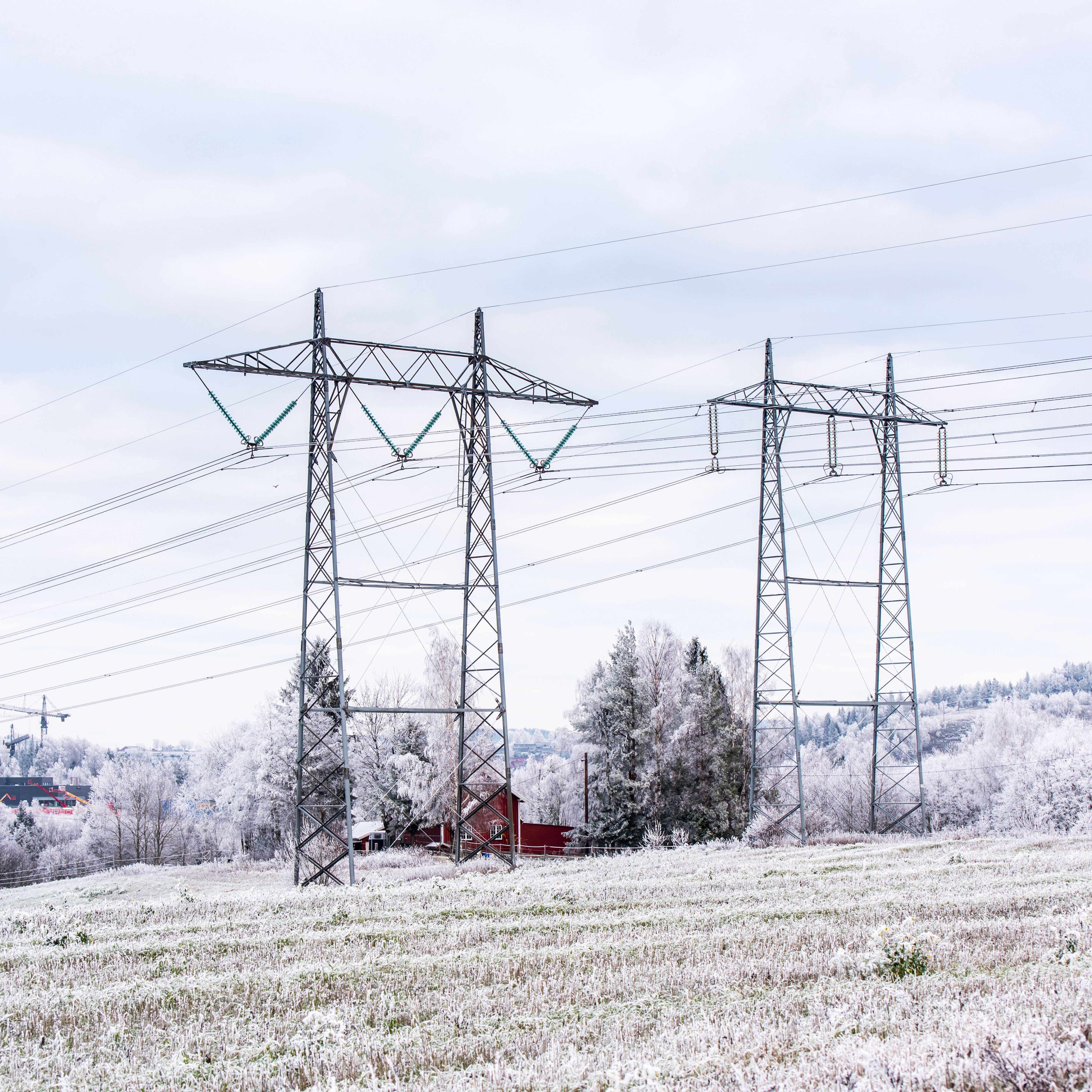 Bilde av strømmaster som står på et snødekket jorde.