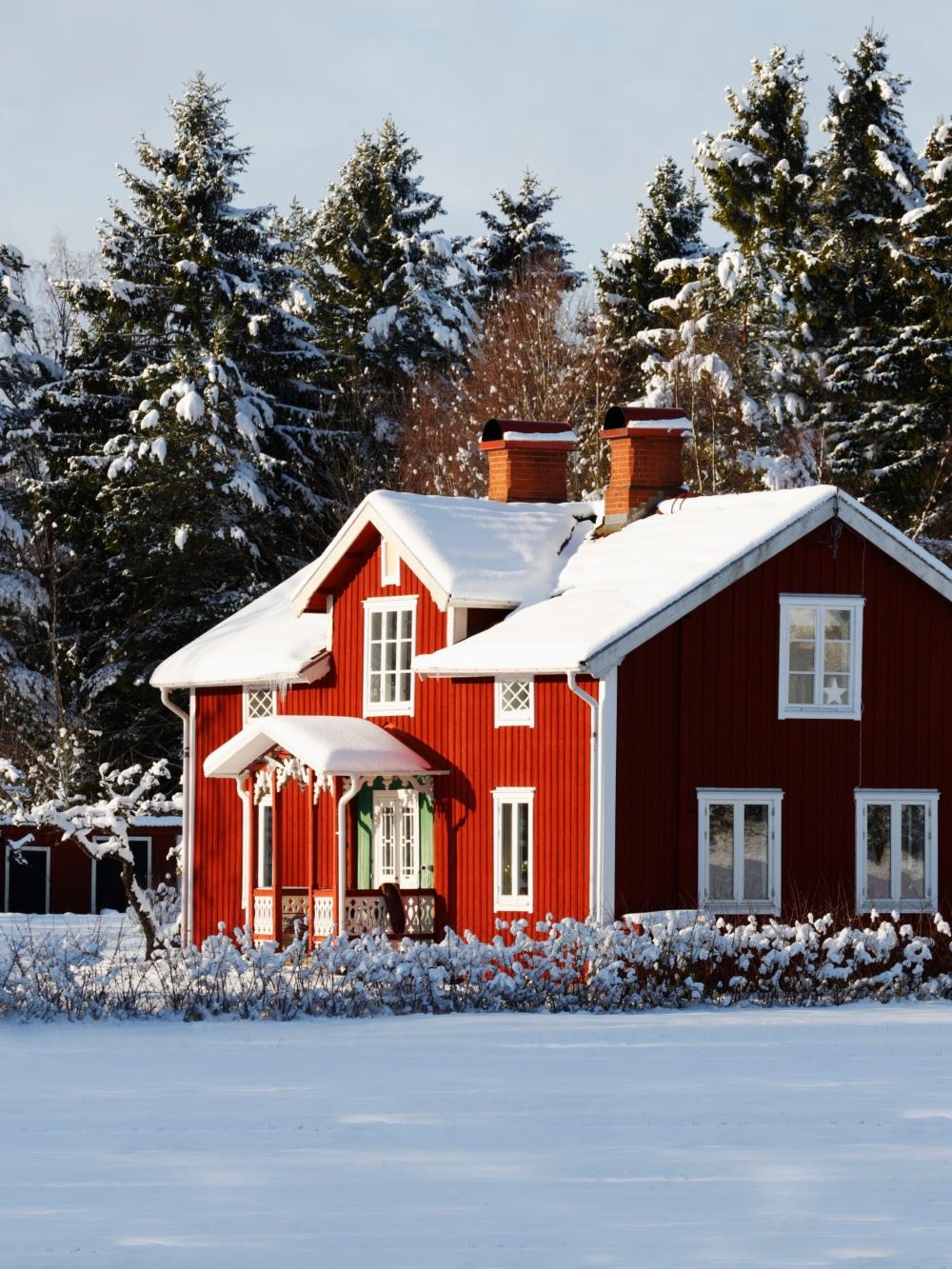 En gammal faluröd svensk trävilla i ett vinterlandskap.